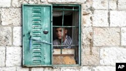ARCHIVO - Un joven palestino observa desde su ventana una manifestación semanal en solidaridad con los residentes del barrio Sheikh Jarrah en Jerusalén oriental, donde las familias palestinas están bajo amenaza inminente de desplazamiento forzado, el viernes 7 de enero de 2022.
