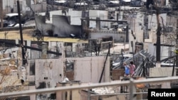 Two people examine a burned house after an inferno destroyed much of the historic Maui resort town of Lahaina, Hawaii, Aug. 13, 2023. (Sandy Hooper/USA Today Network via REUTERS)