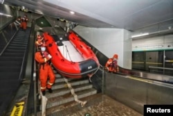 Los trabajadores de rescate ingresan a una estación de metro de la Línea 5 del Metro para inspeccionar las inundaciones luego de las fuertes lluvias en Zhengzhou, provincia de Henan, China, el 26 de julio de 2021. (China Daily vía Reuters).