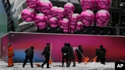 北京一家已經為聖誕節裝飾起來的商場外工人們正在清除積雪。 （2023年12月14日）