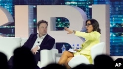 FILE - Twitter CEO Elon Musk, center, speaks with Linda Yaccarino, then the chairman of global advertising and partnerships for NBC, at a conference in Miami Beach, Florida, April 18, 2023.