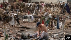 ชายคนหนึ่งกำลังซักเสื้อผ้าในลำธารที่ไหลผ่านกองเศษซากที่หลงเหลือจากภาวะน้ำท่วมซึ่งสร้างความเสียหายครั้งใหญ่ให้หมู่บ้านหนานซิงฟาง ซึ่งตั้งอยู่ชานกรุงปักกิ่ง เมื่อวันที่ 4 ส.ค. 2023. (AP/Ng Han Guan)