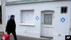 Muškarac prolazi pored Davidovih zvijezda iscrtanih na zidu u Parizu, 31. oktobra 2023.