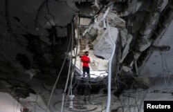 Seseorang berdiri di dalam sebuah bangunan, rusak akibat serangan Israel, di tengah konflik yang sedang berlangsung antara Israel dan Hamas, di Rafah, di selatan Jalur Gaza, 3 Mei 2024. (Foto: Reuters)