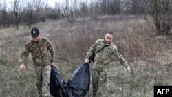 Members of a Ukrainian Civil-Military Cooperation team carry the remains of a Russian soldier in the village of Synykha, in Ukraine's Kharkiv region, April 8, 2023.