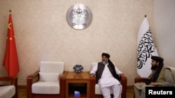 2023年10月19日，塔利班代理商务部长阿齐齐在阿富汗驻中国北京大使馆接受路透社采访时坐在阿富汗伊斯兰酋长国和中国国旗中间。（路透社照片）