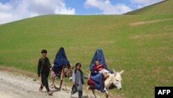 ស្ត្រីអាហ្វហ្គានីស្ថានជិះសត្វលានៅតាមផ្លូវក្បែរភូមិ Shah Mari ខេត្ត Badakhshan កាលពីថ្ងៃទី១ ខែឧសភា ឆ្នាំ២០២៤។ (AFP)