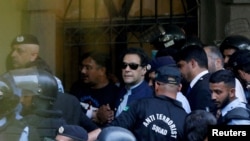 资料照片：2023年5月12日，安全人员在巴基斯坦伊斯兰堡护送前总理伊姆兰·汗（中）在伊斯兰堡高等法院出庭。（路透社照片）