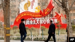 新疆和田居民走過街頭豎立的社會主義核心價值觀的宣傳牌。（2021年3月22日）