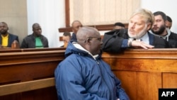 Fulgence Kayishema (kushoto) akizungumza na wakili wake Juan Smuts (kulia) katika Mahakama ya Cape Town, tarehe 26 Mei 2023. Picha na RODGER BOSCH / AFP. 