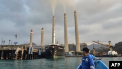 FILE - Seorang nelayan sedang mengamati pembangkit listrik tenaga batu bara (PLTN) Suralaya di Cilegon, provinsi Banten, 31 Oktober 2023. (Ronald SIAGIAN / AFP) 