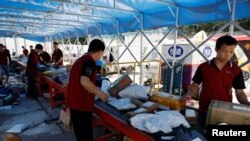 Dostavljači sortiraju pakete na pokretnoj traci, uoči šoping festivala "618", na logističkoj stanici u Pekingu, 12. juna 2023. 