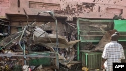 Watu wakipita karibu na jengo la kituo cha matibabu kilichojaa matundu ya risasi kwenye soko liitwalo Souk Sitta, kusini mwa Khartoum, Juni 1, 2023