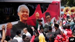 Pendukung mengelilingi bus kampanye calon presiden dari Partai Demokrasi Indonesia Perjuangan (PDIP), Ganjar Pranowo, dan pasangannya Mohammad Mahfud, yang dikenal sebagai Mahfud MD, 19 Oktober 2023. (Foto: AP)