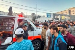 Orang-orang berkumpul di sekitar ambulans yang rusak akibat serangan Israel yang dilaporkan di depan Rumah Sakit Al-Shifa di Kota Gaza pada 3 November 2023. (Foto: AFP)