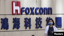 一名女子走過台北鴻海科技集團大樓外的富士康標誌。（2922年11月9日）