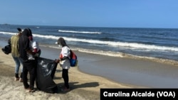 Un grupo de personas participa en labores de limpieza en una playa ubicada en las inmediaciones de la refinería El Palito, en el estado Carabobo, en Venezuela, dos días después de un derrame de crudo.