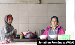 Ali Fernández (izquierda), una migrante venezolana de 28 años, y una migrante mexicana (derecha) sirven el desayuno en el albergue El Buen Samaritano de Ciudad Juárez, México, el 24 de enero de 2024.