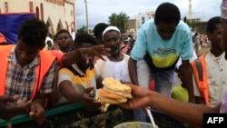 FILE - Sudanese displaced from the town of Sinjah queue to receive food at their makeshift camp in the eastern city of Gedaref, Sudan, Aug. 22, 2024. 