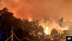 Rohingya refugees watch a fire blaze through their refugee camp at Kutupalong in Cox's Bazar district, Bangladesh, Jan. 7, 2024.