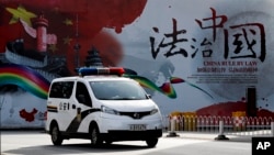 一輛警車駛過北京街頭一面宣傳中國法治的宣傳牆。 （2016年12月28日）