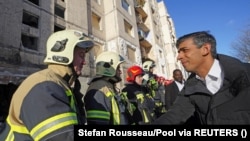 Британський прем’єр-міністр Ріші Сунак з українськими рятувальниками біля будинків зруйнованих російськими бомбардуваннями у Києві. 12 січня 2024 р.