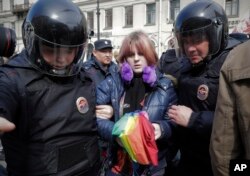 FILE - A gay rights activist holding a rainbow umbrella is detained by police during a rally marking May Day in downtown St. Petersburg, Russia, May 1, 2017.