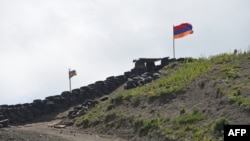 2021 թվականի հունիսի 18-ին Հայաստանի Սոթք գյուղի մոտ արված այս նկարում պատկերված են Ադրբեջանի և Հայաստանի դրոշները, որոնք ծածանվում են երկրների միջև սահմանային անցակետում։ (Լուսանկարը՝ Կարեն Մինասյանի/ AFP)