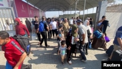 Warga Palestina berkewarganegaraan ganda berjalan di Rafah, Jalur Gaza selatan, perbatasan Rafah-Mesir, dengan harapan mendapat izin meninggalkan Gaza, di tengah konflik Israel-Hamas, 1 November 2023. (REUTERS/ Arafat Barbakh)