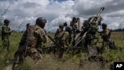 FILE - Ukrainian service members prepare to fire at Russian positions with a U.S.-supplied M777 howitzer in Kharkiv region, Ukraine, July 14, 2022.