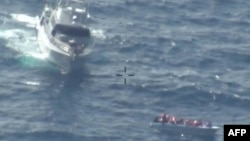 Boti ya doria ikiwa jirani na mashua waliyopanda wahamiaji wakati wa oparesheni ya uokoaji huko Malta Februari 23, 2024. Picha na Kitini / Vikosi vya Wanajeshi vya Malta / AFP