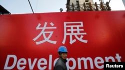 資料照：一名工人走過北京一處建築工地的宣傳標語。 （2014年12月12日）