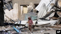 Seorang anak Palestina berjalan melewati pabrik yang hancur akibat pengeboman Israel di Jalur Gaza di Deir al Balah, 13 Januari 2024. (Foto: AP)