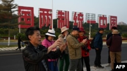 中国福建厦门竖立起一个台湾金门岛可以看到的“一国两制统一中国”的大型标语牌，旅游者在前拍照。（2024年1月12日）