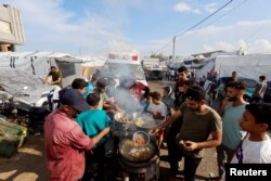 Warga Palestina memasak makanan di tenda kamp yang menampung para pengungsi Palestina, di tengah konflik Israel-Hamas, di Khan Younis, selatan Jalur Gaza, 14 November 2023. (REUTERS/Mohammed Salem)