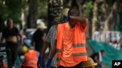 Công nhân lát gạch vỉa hè lau mồ hôi trong khi làm việc dưới cái nóng thiêu đốt ở Bắc Kinh hôm 10/7/2023. 