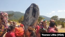 Masyarakat berpose dengan latar arca megalit Palindo yang berada di Desa Kolori, Kecamatan Lore Barat, Kabupaten Poso, Sulawesi Tengah, Selasa, 10 Oktober 2023. (Foto: VOA/Yoanes Litha)