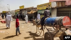 Watu wakimpita mwanamume aliyeendesha mkokoteni unaosukumwa na punda huko kusini mwa jiji la Khartoum, tarehe 1 Juni 2023. Picha na AFP. 