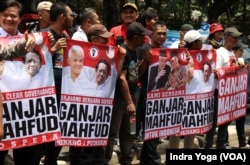 Para pendukung pasangan capres-cawapres PDI-Perjuangan Ganjar Pranowo dan Mahfud MD membawa poster-poster di luar kantor DPP PDI-P di Jakarta, Rabu, 18 Oktober 2023. (Foto: Indra Yoga/VOA)