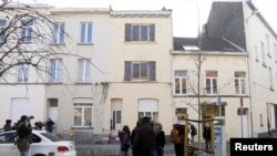 Reporters stand in front of an apartment (C) in the Brussels district of Forest where a gunman was shot dead by Belgian police on Tuesday after a raid on the apartment linked to investigations into November's Islamist attacks in Paris, March 16, 2016. 