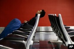 FILE - A man sleeps at the Los Angeles International Airport.