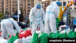 西藏拉萨街头身穿防护服的大白为被封在家中的居民们整理食品袋。（2022年9月29日）