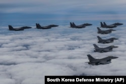 In this photo provided by South Korea Defense Ministry, South Korean Air Force's F15K fighter jets and U.S. Air Force's F-16 fighter jets, fly in formation during a joint drill in an undisclosed location in South Korea, Tuesday, Oct. 4, 2022. The South Ko
