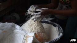 FILE - A vendor measures wheat flour in a cup for retail at a market in Ibafo, Ogun State, southwest Nigeria, on March 14, 2022. 