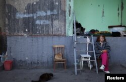 Natalia Pasternak (68), duduk di dekat kucing yang ditinggalkan oleh keluarga yang melarikan diri dari perang di lingkungan Pasternak di Saltivka utara, salah satu daerah perumahan paling rusak di Kharkiv, Ukraina 18 Juli 2022. (REUTERS/Nacho Doce)