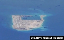 FILE - Chinese dredging vessels are purportedly seen in the waters around Fiery Cross Reef in the disputed Spratly Islands in the South China Sea in this still image from video taken by a P-8A Poseidon surveillance aircraft provided by the United States Navy.