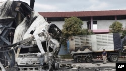 A Thai officer stands beside the burnt down oil tanker at a gas station in Pattani province, southern Thailand, Aug. 17, 2022. 