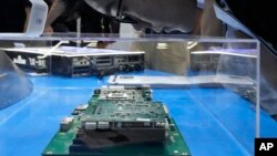 A visitor examines a computer chipset at the booth for Chinese semiconductor and chip developer Kunlunxin during the World AI Conference in Shanghai, Wednesday, July 5, 2023. (AP Photo/Ng Han Guan)