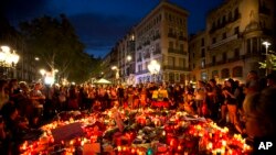 People gather at a memorial tribute of flowers, messages and candles to the victims on Barcelona's historic Las Ramblas promenade on the Joan Miro mosaic, embedded in the pavement where the van stopped after killing at least 13 people in Barcelona , Spain, Friday, Aug. 18, 2017. (AP Photo/Emilio Morenatti)