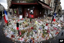 FILE - Flowers and candle tributes are placed at the Restaurant Le Carillon in Paris, Nov. 19, 2015, after last Friday's attacks.